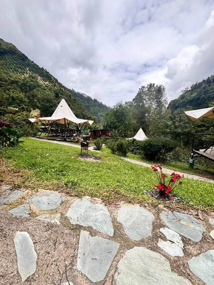 Sendero de piedra junto a zona de fogata con flores rojas