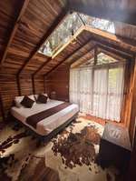 Cama y ventanal de la cabaña Refugio del Viento con vista al bosque